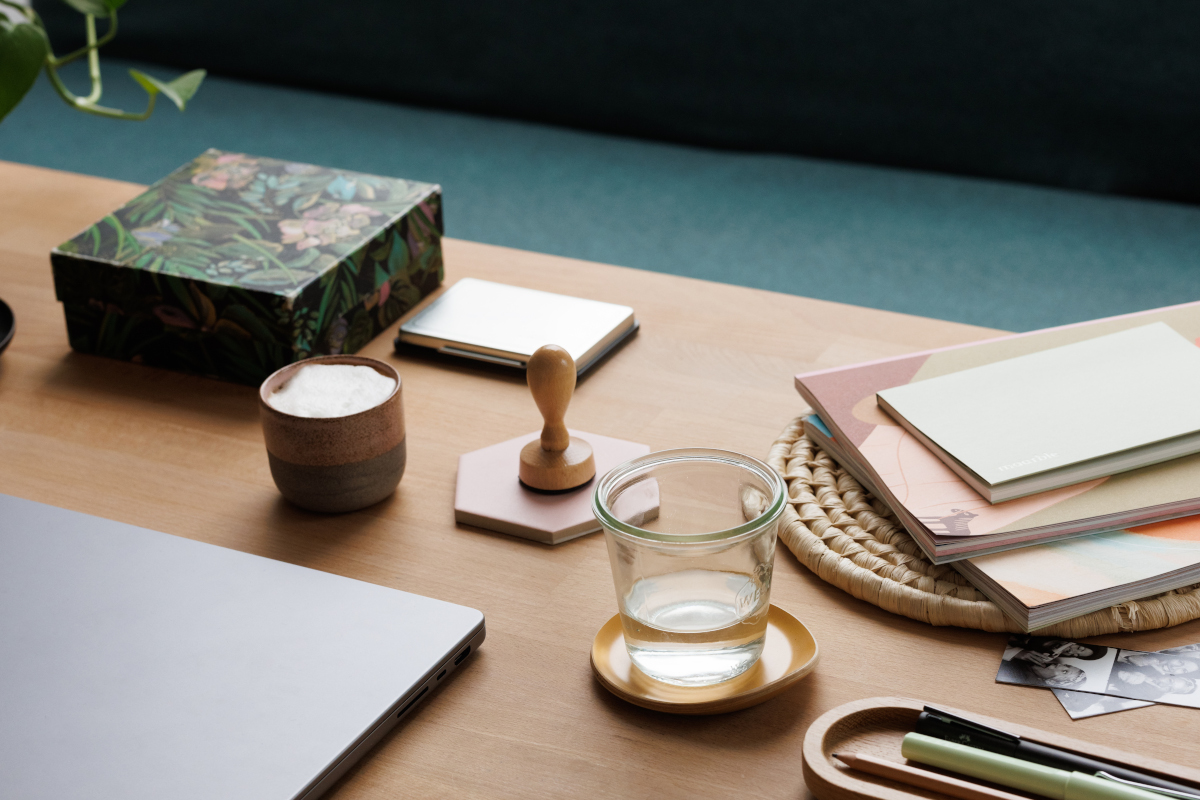 Schreibtisch mit Laptop, Notizblock und Wasserglas